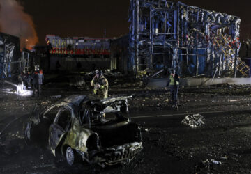 Rescue workers walk in front of a car and a building destroyed by a Russian strike in Zaporizhzhia, Ukraine, December 6, 2024. (AP Photo/Kateryna Klochko)