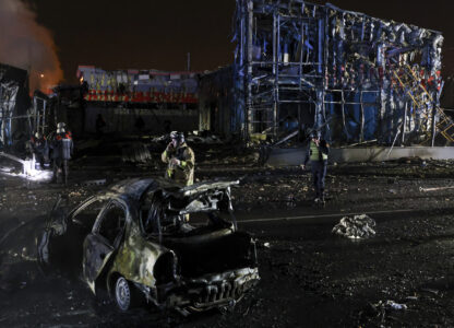 Rescue workers walk in front of a car and a building destroyed by a Russian strike in Zaporizhzhia, Ukraine, December 6, 2024. (AP Photo/Kateryna Klochko)