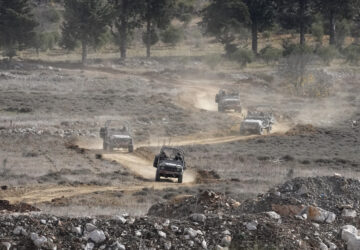 Israeli armoured vehicles maneuver next to the security fence near the so-called Alpha Line that separates the Israeli-annexed Golan Heights from Syria, in the town of Majdal Shams, Wednesday, Dec. 11, 2024. (AP Photo/Matias Delacroix)