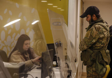 A Syrian opposition fighter waits to charge his mobile phone in Damascus, Syria, Tuesday, Dec. 10, 2024. (AP Photo/Omar Sanadiki)