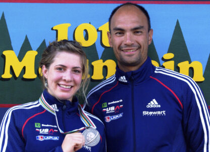 In this 2009 photo provided by Karen Gorman, biathlete Grace Boutot, left, of Fort Kent, Maine, displays her silver medal from the Youth Women Biathlon World Championships, while standing with coach Gary Colliander, right, in Fort Kent. (Karen Gorman via AP)