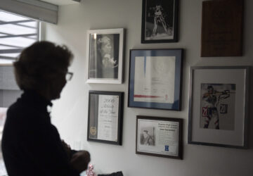 Two-time Olympian Joan Wilder looks at memorabilia at her home on Nov. 22, 2024, in Bend, Ore., including an image of her competing at bottom right. (AP Photo/Jenny Kane)