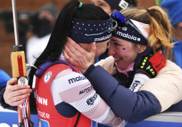 FILE — Joanne Reid, left, of the United States, and compatriot Deedra Irwin embrace at the finish line during the women's 4 x 6 km relay race at the biathlon World Cup in Anterselva, Italy, Jan. 22, 2022. (AP Photo/Matthias Schrader, File)