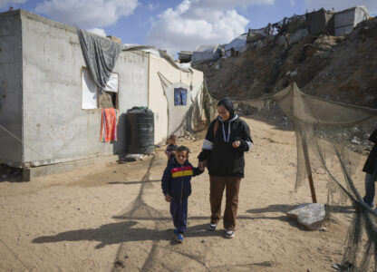 Reem Ajour walks with her son, Wael, at a camp outside Zuweida, Gaza Strip, Nov. 20, 2024. (AP Photo/Abdel Kareem Hana)