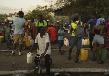 People lineup to collect water Wednesday, Dec. 18, 2024 in the French Indian Ocean island of Mayotte. (AP Photo/Adrienne Surprenant)