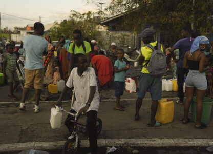 People lineup to collect water Wednesday, Dec. 18, 2024 in the French Indian Ocean island of Mayotte. (AP Photo/Adrienne Surprenant)