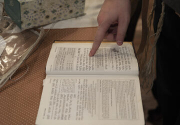 Dov Marcus points to prayers as he reads from the Jewish prayer book in Teaneck, N.J., on Friday, Dec. 20, 2024. (AP Photo/Luis Andres Henao)