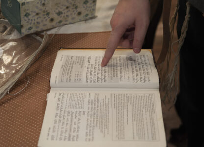 Dov Marcus points to prayers as he reads from the Jewish prayer book in Teaneck, N.J., on Friday, Dec. 20, 2024. (AP Photo/Luis Andres Henao)