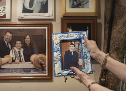 Debbie Marcus shows a framed photo of her son, Dov Marcus, taken at his Bar Mitzvah on display at their family home in Teaneck, N.J., on Friday, Dec. 20, 2024. (AP Photo/Luis Andres Henao)