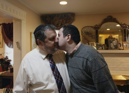 Dov Marcus, right, kisses his father, Robert Marcus, in Teaneck, N.J., on Friday, Dec. 20, 2024. (AP Photo/Luis Andres Henao)