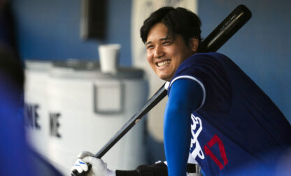 FILE- Los Angeles Dodgers designated hitter Shohei Ohtani smiles in the dugout before a spring training baseball game against the Los Angeles Angels in Phoenix, Tuesday, March 5, 2024. (AP Photo/Ashley Landis, File)