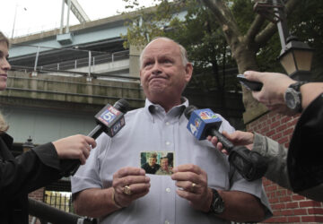 FILE - Ken Fairben holds a photo showing his son Keith, left, a victim of the Sept, 11, attacks, as he talks with reporters Oct. 15, 2012, outside Fort Hamilton Army base in Brooklyn, N.Y. (AP Photo/Bebeto Matthews, File)