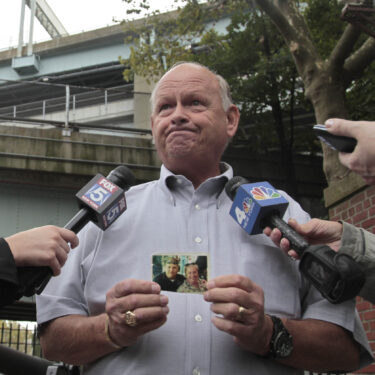 FILE - Ken Fairben holds a photo showing his son Keith, left, a victim of the Sept, 11, attacks, as he talks with reporters Oct. 15, 2012, outside Fort Hamilton Army base in Brooklyn, N.Y. (AP Photo/Bebeto Matthews, File)