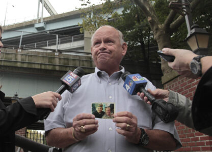 FILE - Ken Fairben holds a photo showing his son Keith, left, a victim of the Sept, 11, attacks, as he talks with reporters Oct. 15, 2012, outside Fort Hamilton Army base in Brooklyn, N.Y. (AP Photo/Bebeto Matthews, File)