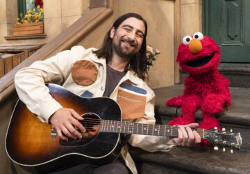 This image released by Sesame Workshop shows singer Noah Kahan, left, with muppet character Elmo on the set of 