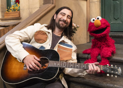 This image released by Sesame Workshop shows singer Noah Kahan, left, with muppet character Elmo on the set of 