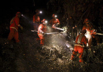 A California Department of Corrections hand crew works containment lines ahead of the Palisades Fire Tuesday, Jan. 14, 2025 in Santa Monica, Calif. (AP Photo/Ethan Swope)