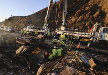 Workers pull a burnt car out of the wreckage of a home destroyed by the Palisades Fire, Tuesday, Jan. 14, 2025, in Malibu, Calif. (AP Photo/Ethan Swope)