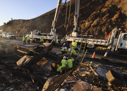 Workers pull a burnt car out of the wreckage of a home destroyed by the Palisades Fire, Tuesday, Jan. 14, 2025, in Malibu, Calif. (AP Photo/Ethan Swope)