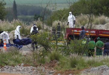 Forensic service workers carry bodies in blue body bags during a rescue operation to rescue miners from below ground in an abandoned gold mine in Stilfontein, South Africa, Wednesday, Jan. 15, 2025. (AP Photo/Themba Hadebe)