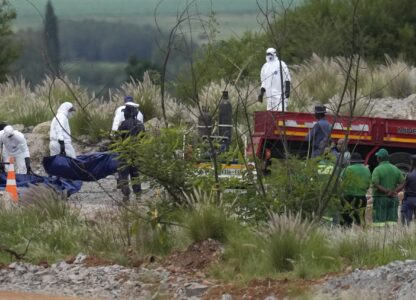 Forensic service workers carry bodies in blue body bags during a rescue operation to rescue miners from below ground in an abandoned gold mine in Stilfontein, South Africa, Wednesday, Jan. 15, 2025. (AP Photo/Themba Hadebe)