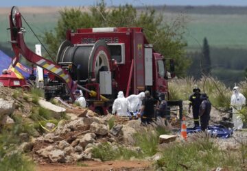 Forensic service workers carry body remains in blue body bags during a rescue operation to rescue miners from below ground in an abandoned gold mine in Stilfontein, South Africa, Wednesday, Jan. 15, 2025. (AP Photo/Themba Hadebe)