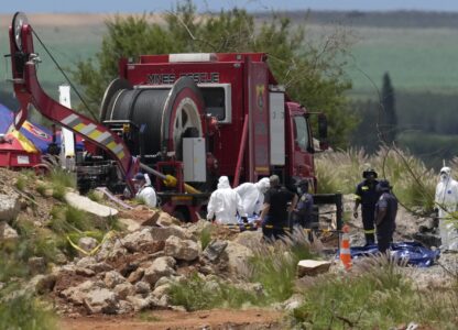 Forensic service workers carry body remains in blue body bags during a rescue operation to rescue miners from below ground in an abandoned gold mine in Stilfontein, South Africa, Wednesday, Jan. 15, 2025. (AP Photo/Themba Hadebe)