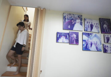 Danaya Phonphayung walks in front of her partner Sunma Piamboon next to their wedding photos at their home in Bangkok, Thailand, on Jan. 13, 2025. (AP Photo/Sakchai Lalit)