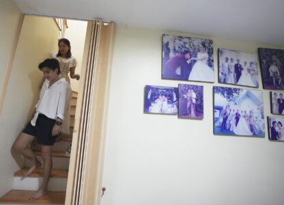 Danaya Phonphayung walks in front of her partner Sunma Piamboon next to their wedding photos at their home in Bangkok, Thailand, on Jan. 13, 2025. (AP Photo/Sakchai Lalit)