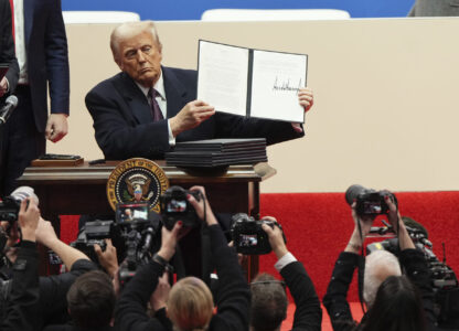 President Donald Trump holds up an executive order after signing it at an indoor Presidential Inauguration parade event in Washington, Monday, Jan. 20, 2025. (AP Photo/Matt Rourke)