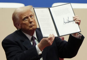 President Donald Trump holds up an executive order after signing it at an indoor Presidential Inauguration parade event in Washington, Monday, Jan. 20, 2025. (AP Photo/Matt Rourke)