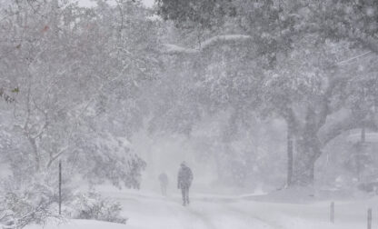 People walk as snow falls in New Orleans, Tuesday, Jan. 21, 2025. (AP Photo/Gerald Herbert)