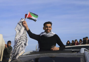 FILE - A man waves a Palestinian flag as he returns home to Rafah, after a ceasefire deal between Israel and Hamas went into effect, in Rafah, Gaza Strip, Jan. 19, 2025. (AP Photo/Mariam Dagga, File)