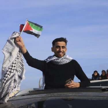 FILE - A man waves a Palestinian flag as he returns home to Rafah, after a ceasefire deal between Israel and Hamas went into effect, in Rafah, Gaza Strip, Jan. 19, 2025. (AP Photo/Mariam Dagga, File)