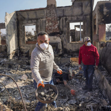 Homeowner David Marquez, left, holds a metal detector as he shows recovered metal items found with his father, Juan Pablo Alvarado, right, inside the walls of their multi-generational home in the aftermath of the Eaton Fire, Sunday, Jan. 19, 2025, in Altadena, Calif. (AP Photo/Damian Dovarganes)