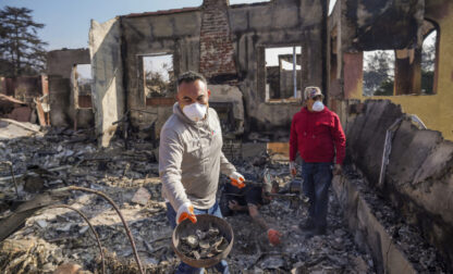 Homeowner David Marquez, left, holds a metal detector as he shows recovered metal items found with his father, Juan Pablo Alvarado, right, inside the walls of their multi-generational home in the aftermath of the Eaton Fire, Sunday, Jan. 19, 2025, in Altadena, Calif. (AP Photo/Damian Dovarganes)