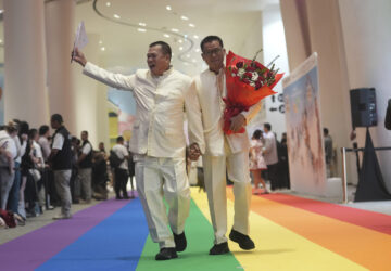 A just-married couple from the LGBTQ+ community walks on rainbow carpet in Bangkok, Thailand, Thursday, Jan. 23, 2025, on the first day a law took effect granting them the same rights as heterosexual couples. (AP Photo/Sakchai Lalit)