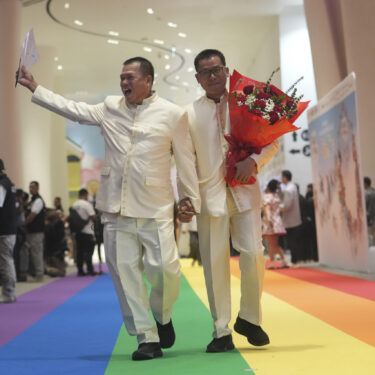 A just-married couple from the LGBTQ+ community walks on rainbow carpet in Bangkok, Thailand, Thursday, Jan. 23, 2025, on the first day a law took effect granting them the same rights as heterosexual couples. (AP Photo/Sakchai Lalit)