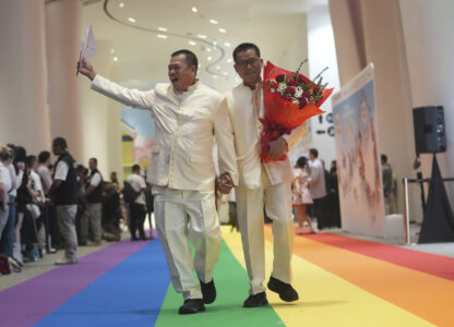 A just-married couple from the LGBTQ+ community walks on rainbow carpet in Bangkok, Thailand, Thursday, Jan. 23, 2025, on the first day a law took effect granting them the same rights as heterosexual couples. (AP Photo/Sakchai Lalit)