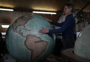 FILE - Peter Bellerby, the founder of Bellerby & Co. Globemakers, holds a globe at a studio in London, Tuesday, Feb. 27, 2024. (AP Photo/Kin Cheung, File)