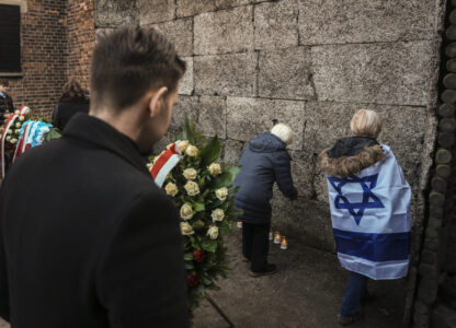 Survivors and relatives place candles near the Death Wall during a ceremony at the Auschwitz-Birkenau former Nazi German concentration and extermination camp, in Oswiecim, Poland, Monday, Jan. 27. 2025. (AP Photo/Oded Balilty)