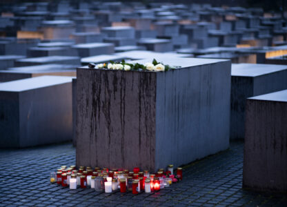 Candles and flowers are placed by a concrete slabs on the occasion of the International Holocaust Remembrance Day, marking the liberation of the Nazi death camp Auschwitz - Birkenau, at the Holocaust Memorial in Berlin, Germany, Monday, Jan. 27, 2025. (AP Photo/Markus Schreiber)