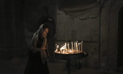 A woman lights candles at the Church of the Holy Sepulchre, where many Christians believe Jesus was crucified, buried and rose from the dead, in the Old City of Jerusalem, Tuesday, Jan. 28, 2025. (AP Photo/Mahmoud Illean)