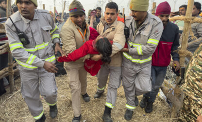 Security officers carry a woman out from the site of a stampede at the Sangam, the confluence of the Ganges, the Yamuna and the mythical Saraswati rivers, on 