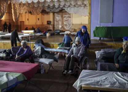 A volunteer helps a woman on a wheelchair at a center for displaced people in Pavlohrad, Ukraine, Saturday, Feb. 1, 2024. (AP Photo/Evgeniy Maloletka)