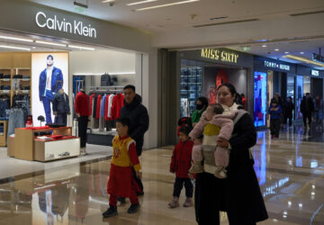 Shoppers tour by Calvin Klein and Tommy Hilfiger fashion boutiques, which are owned by PVH Group, at a shopping mall in Beijing, Tuesday, Feb. 4, 2025. (AP Photo/Andy Wong)