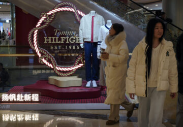 Women walk by a fashion display of Tommy Hilfiger, which is owned by PVH Group, at a shopping mall in Beijing, Tuesday, Feb. 4, 2025. (AP Photo/Andy Wong)