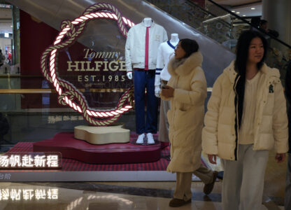 Women walk by a fashion display of Tommy Hilfiger, which is owned by PVH Group, at a shopping mall in Beijing, Tuesday, Feb. 4, 2025. (AP Photo/Andy Wong)