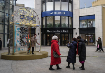 Women take a picture with a decoration on display near an American fashion boutiques at an outdoor shopping mall in Beijing, Tuesday, Feb. 4, 2025. (AP Photo/Andy Wong)