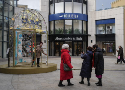 Women take a picture with a decoration on display near an American fashion boutiques at an outdoor shopping mall in Beijing, Tuesday, Feb. 4, 2025. (AP Photo/Andy Wong)